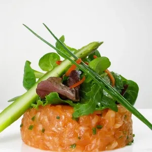 La Distinction, une salle de réception prisée chez Mariage Elegant, présente une élégante entrée de tartare de saumon disposée avec soin. Le plat est agrémenté de jeunes pousses vertes fraîches, d